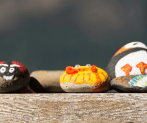 Brightly painted river rocks on a wood table.