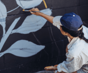 Woman painting a black and while mural on a garden wall.