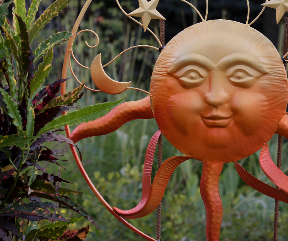 Whimsical garden art of a warmly colored hammered metal sun.