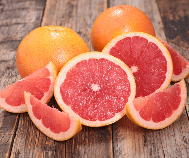 Fresh harvested Ruby Grapefruit sliced on a wooden table.