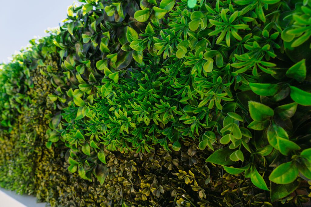 Up close view of a faux plant privacy hedge made of fake plants. These are easy to install, creating fast privacy screens.
