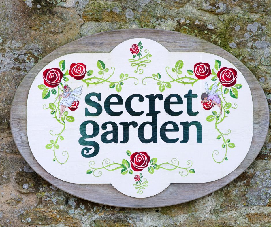 A garden sign with the words "Secret garden" surrounded by red roses.
