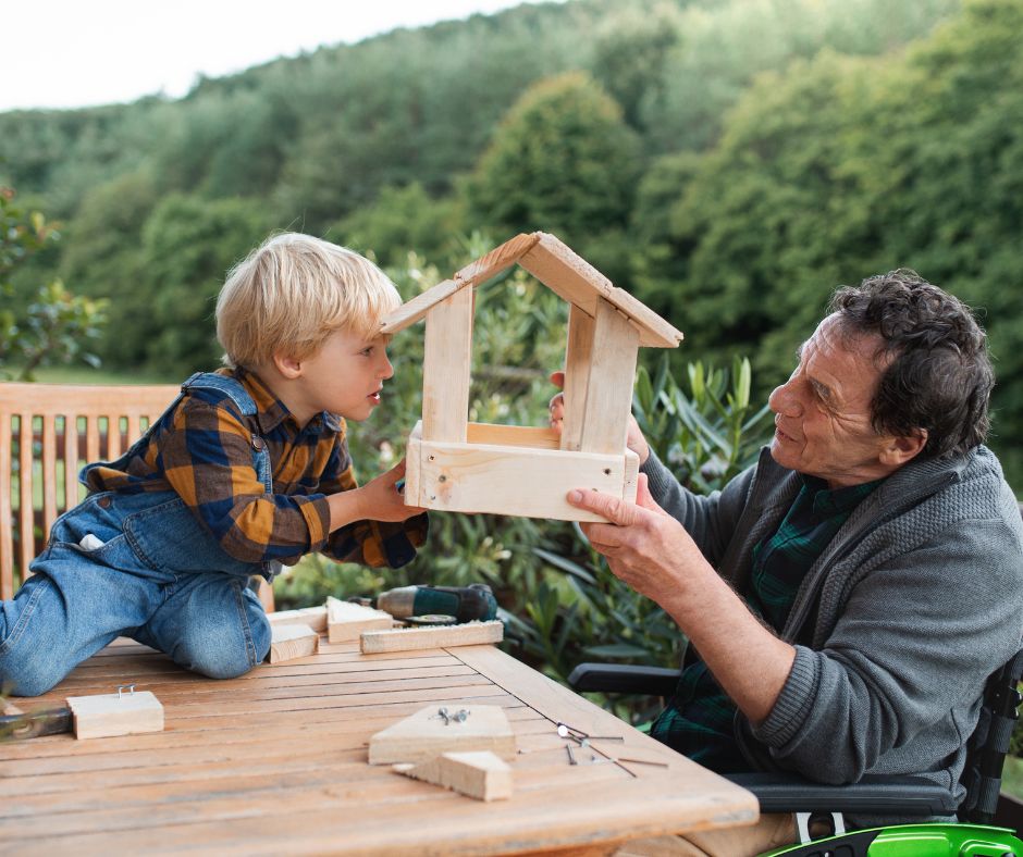 A man and a little boy looking at a homemade bird house they are working on together.