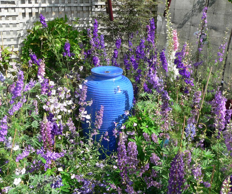 A homemade blue ceramic pot fountain in a flower garden.