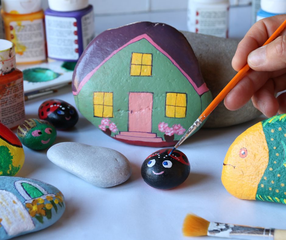 Dainty painted garden rocks including ladybugs, fish and a house.