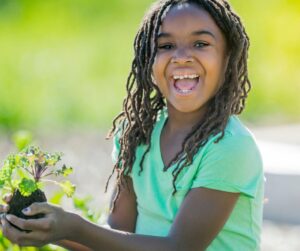 A young girl having a great time planting kale seedlings in the garden.