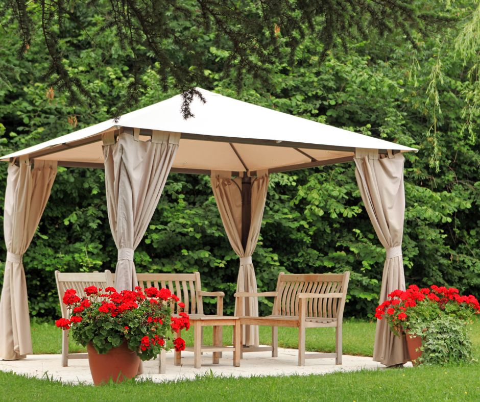A freestanding garden structure with outdoor curtains proving shade and privacy for a seating area.