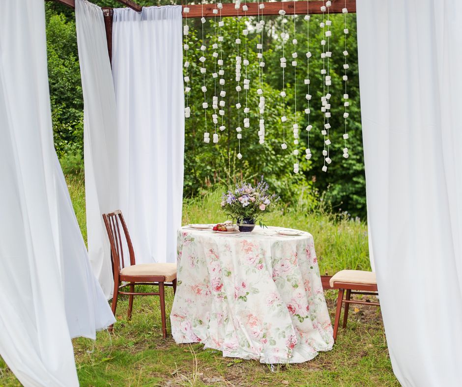 A romantic outdoor outdoor seating area for 2 featuring outdoor curtains hanging from a pergola for privacy.