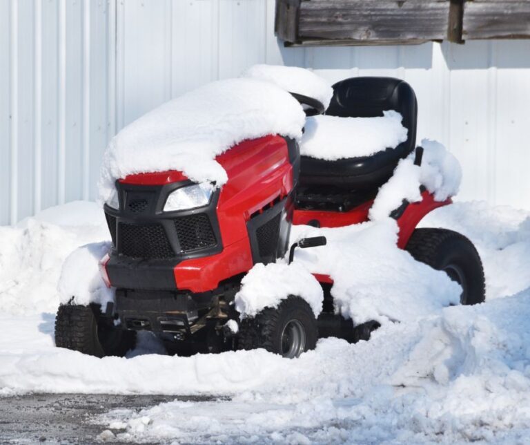 A red riding lawn mower improperly winterized left out in in the snow.
