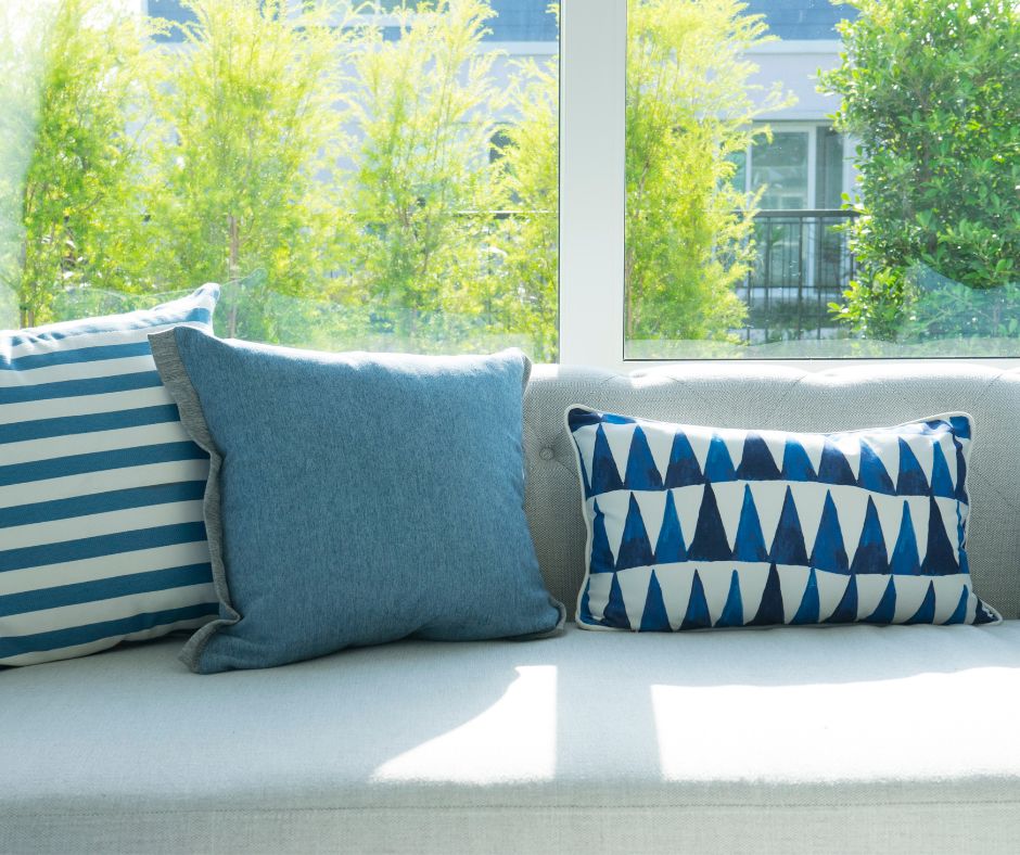 Three throw pillows in a seaside color palette of white and light blue.