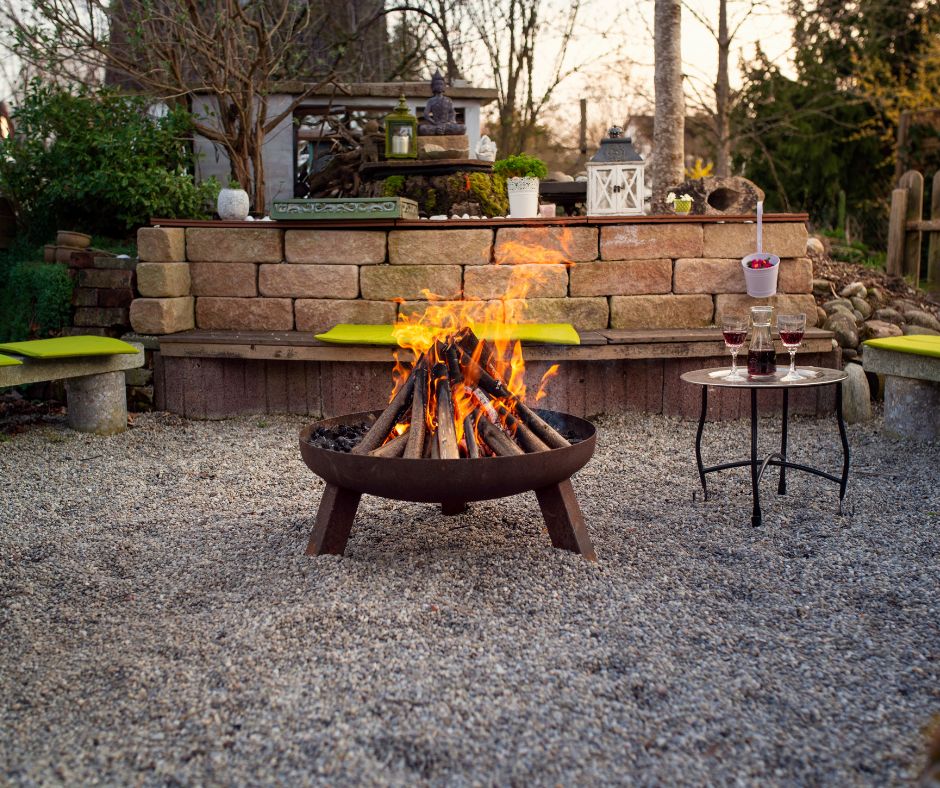 A fire burning in a fire pit placed in a rustic patio featuring built in seating.