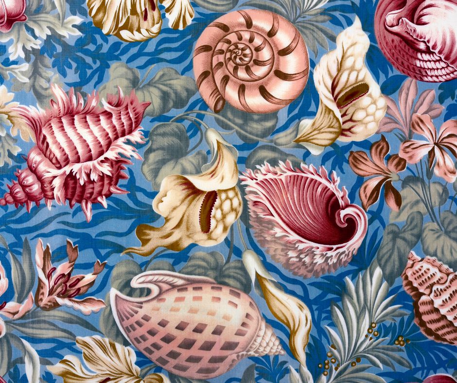 Coastal theme fabric featuring a light blue background, seashells in shades of pink, seaweed and green plants, and detailed while peace lily flowers.