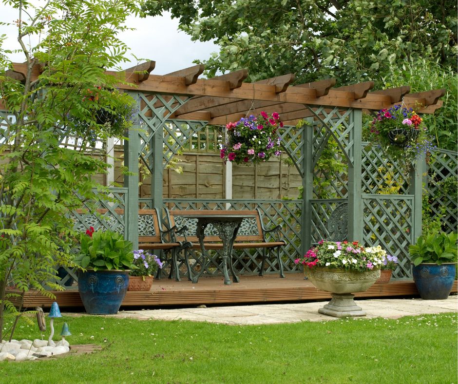Freestanding pergola with lattice sides in a garden and providing shade to a dinning set.