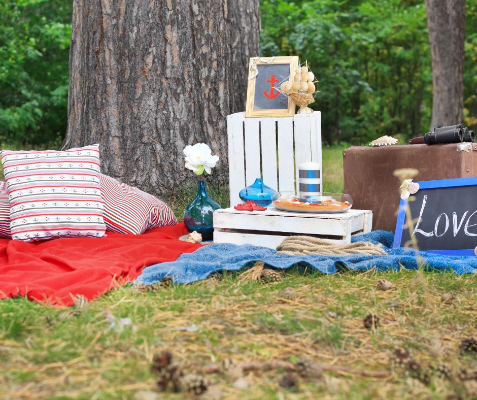 A temporary seaside themed sitting area consisting with blue and white blankets, pillows and beachy accessories.
