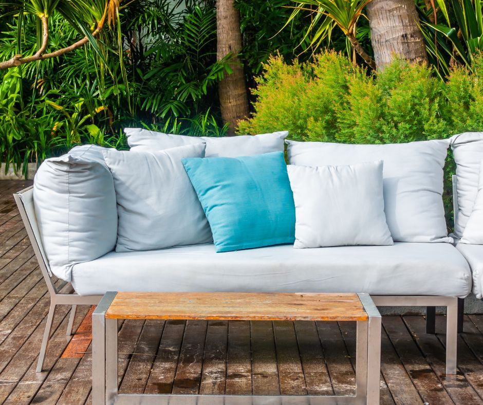 An airy open space coastal style reading space. A soft seafoam blue couch and pillows and light wood table.