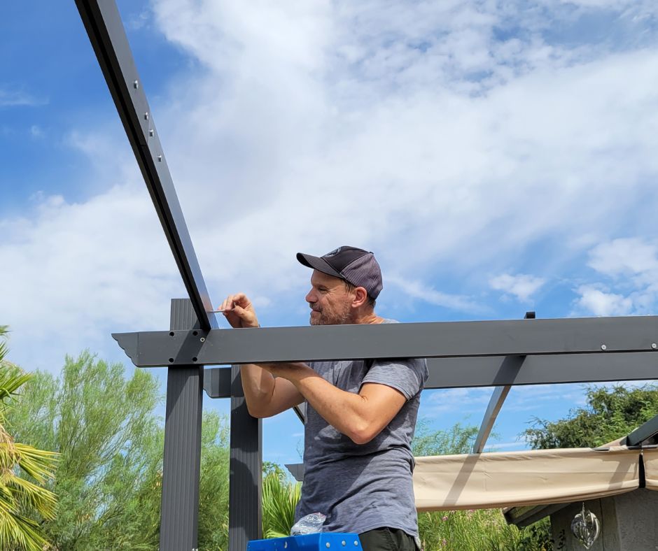 Man installing a black metal pergola.