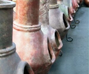 A row of traditional clay chimeneas at a garden shop.