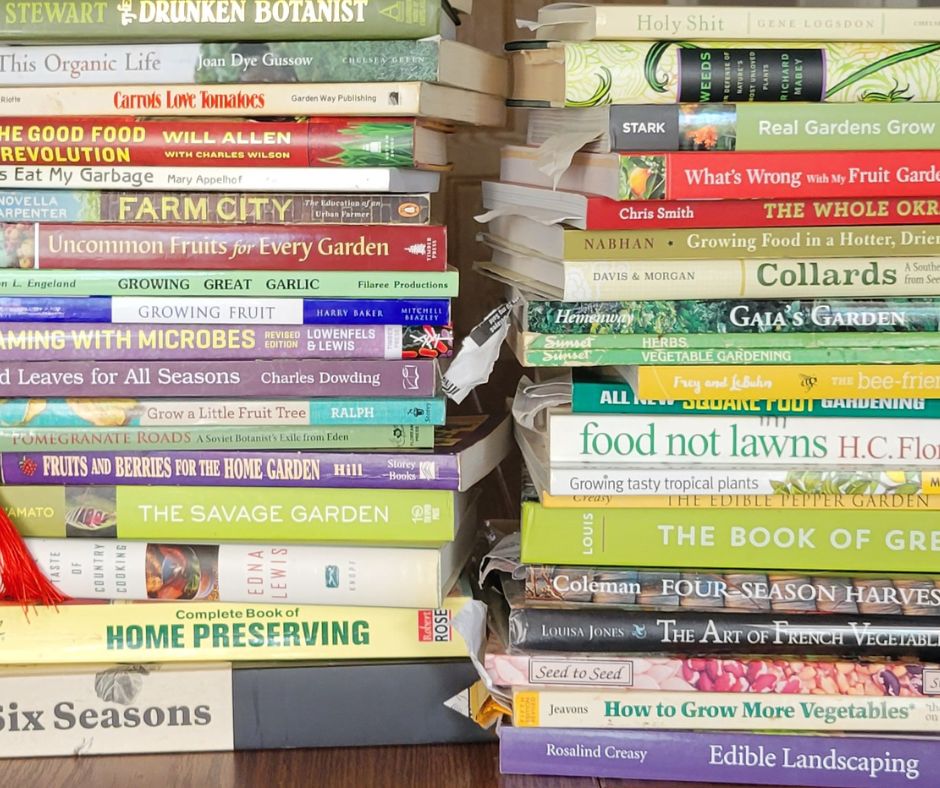 Two stacks of gardening books and other books a green thumb would collect. Including Food Not Lawns, Collards, and Home Preserving.