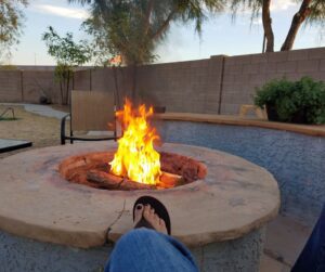 A foot being warmed on the edge of a large fire pit.