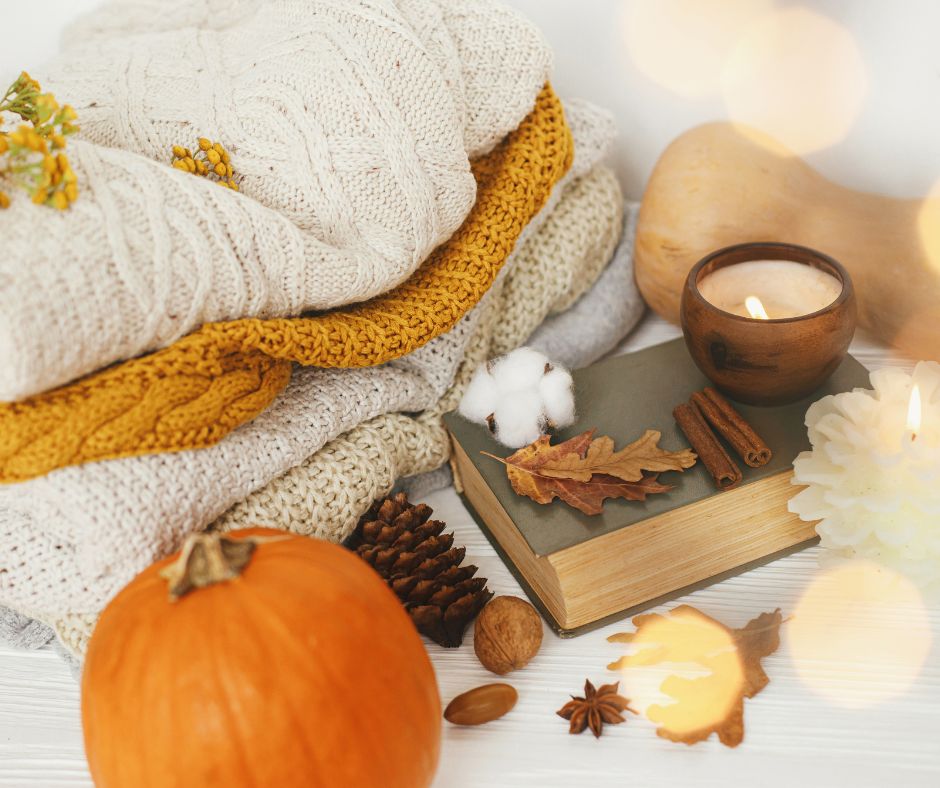 Accessories for a cozy outdoor reading nook. A candle, four neutral knit blankets and winter squash.
