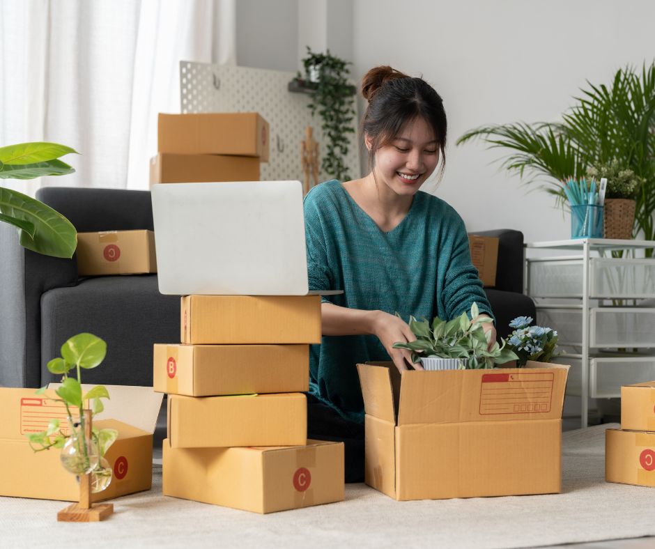 A woman joyfully unpacking boxes of plants.