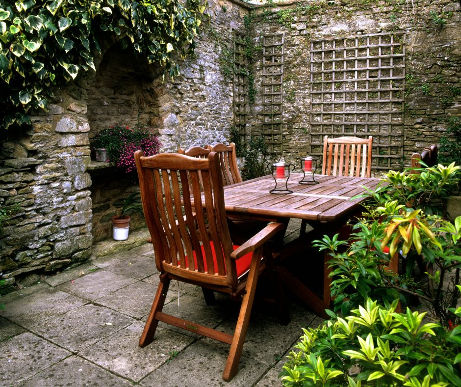 A stone courtyard sitting area with a wooden table set in the center.