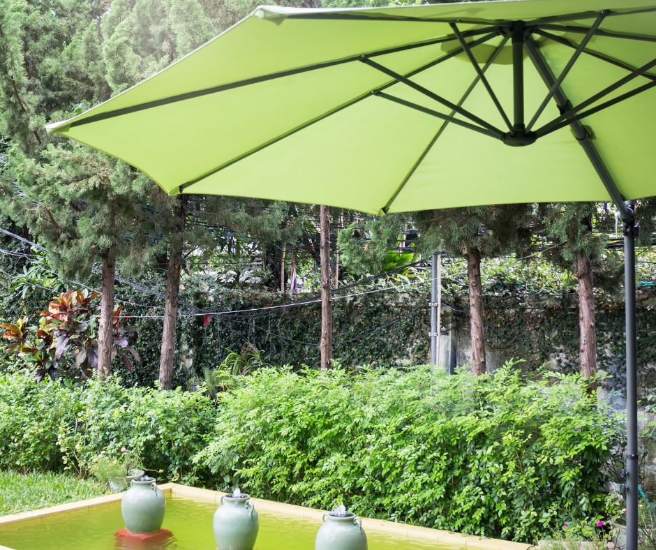 A green umbrella providing shade for garden and pond.