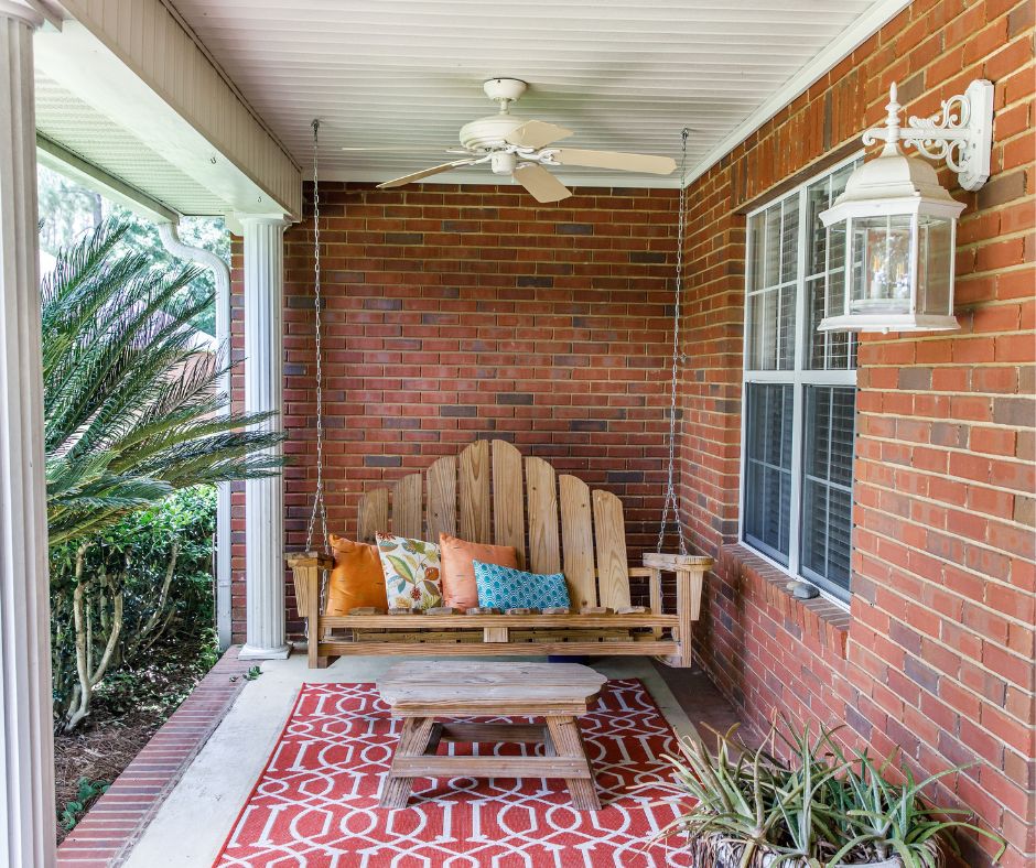 A simple patio reading nook. Swinging bench, potted plants, colorful patterned rugs and pillows.