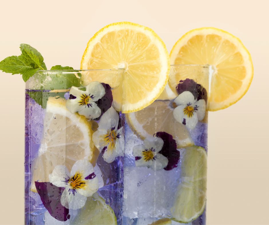 Two glasses of lemon aide with pansies, mint and lemon slices.