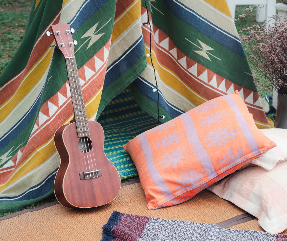 Bohemian accessories including a guitar, pillows and blanket in rich colors and patterns.
