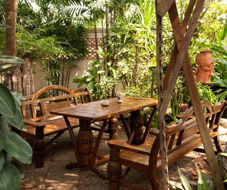 A private backyard sitting area made of wooden table and two benches. Surrounded by plants and lattice for budget friendly privacy.