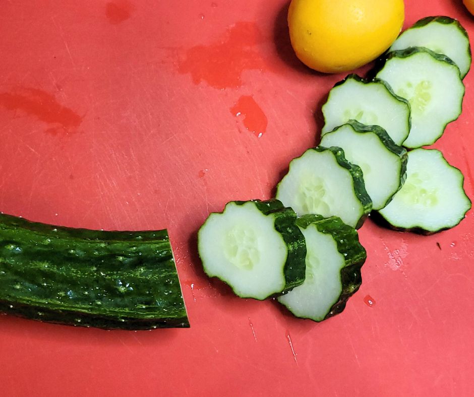 Sliced cucumber and lemon on a red mat.