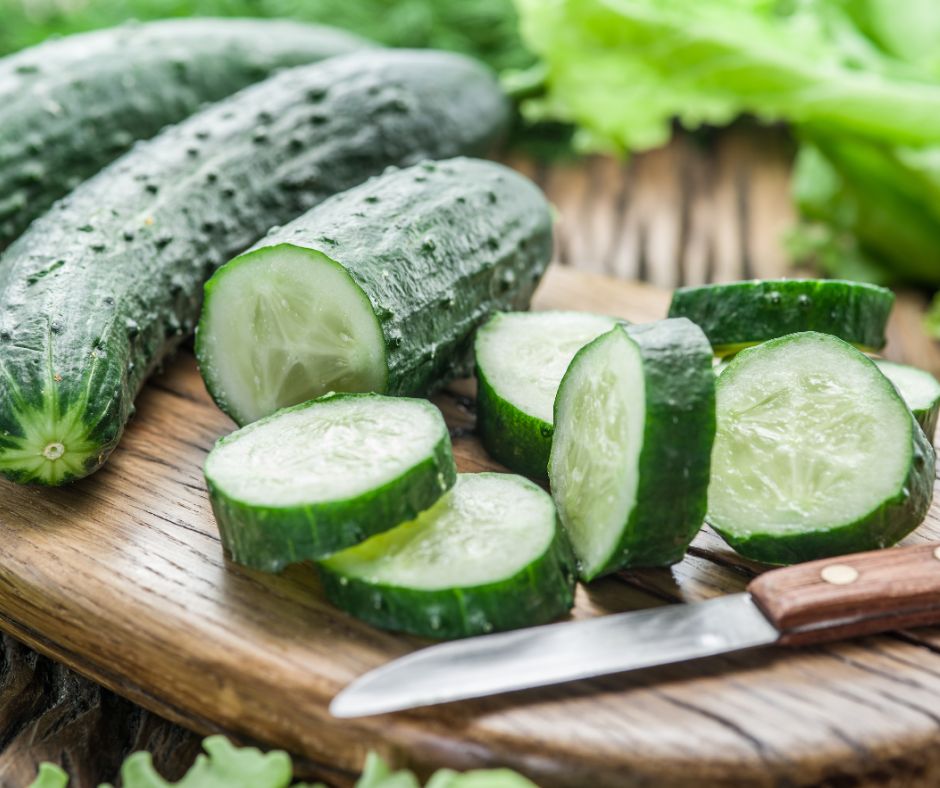 Freshly harvested sliced cucumbers on a wooden surface.