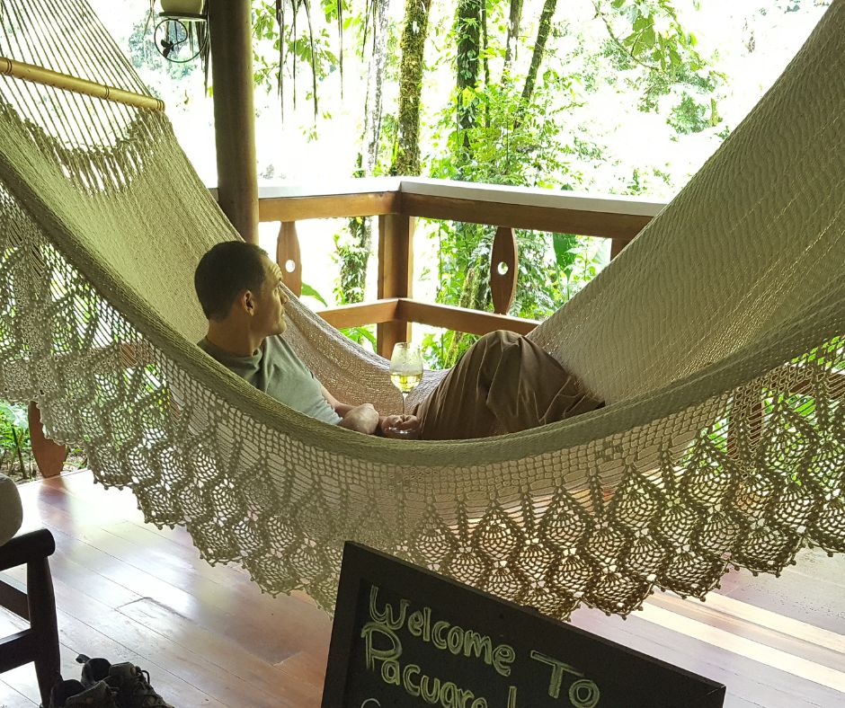 A man enjoying the view from a white woven cord patio hammock.