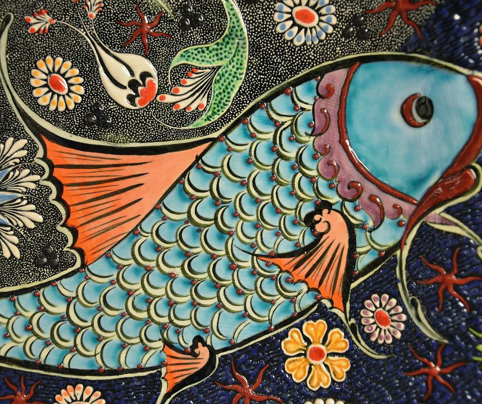 A brightly colored ceramic fish mosaic on a garden wall.