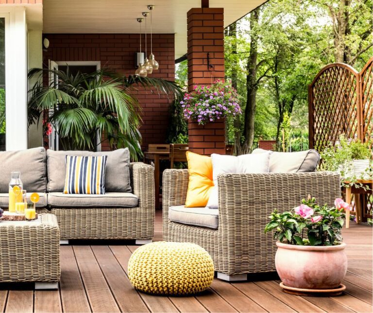 An outdoor patio seating area with privacy screens of potted plants and a free standing lattice wall.