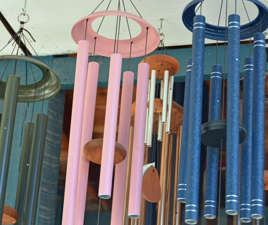 A selection of green, pink, and blue metal wind chimes.