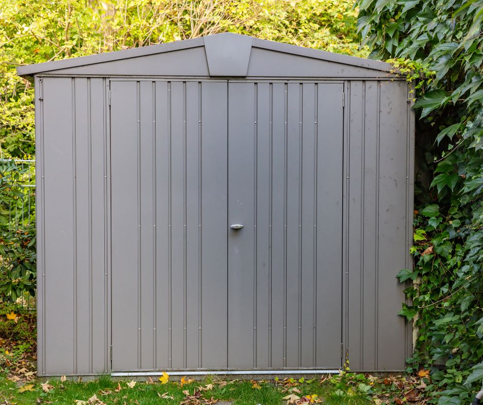 A grey metal garden shed in a backyard