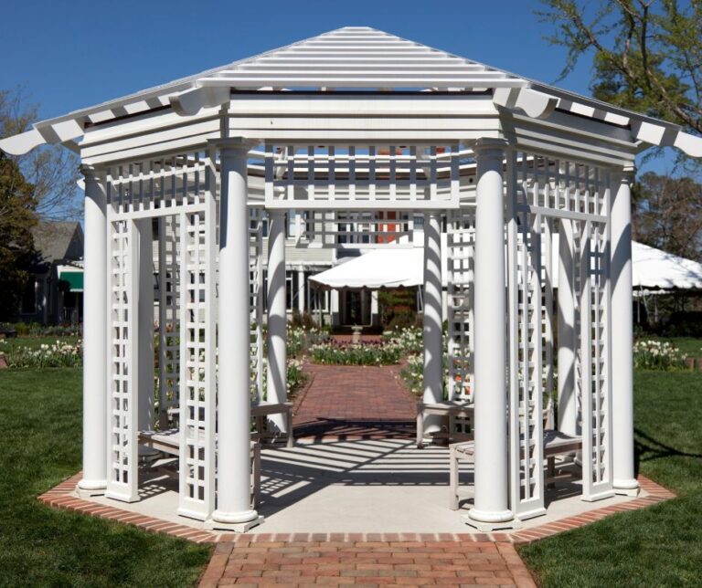 A white gazebo with extensive lattice work providing privacy.