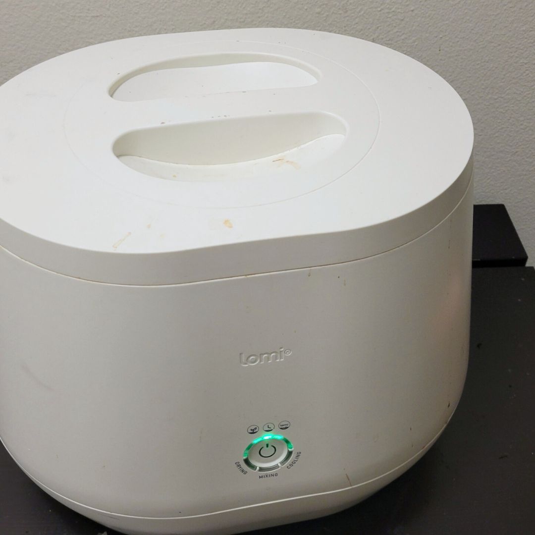 A white Lomi Composter making compost indoors.