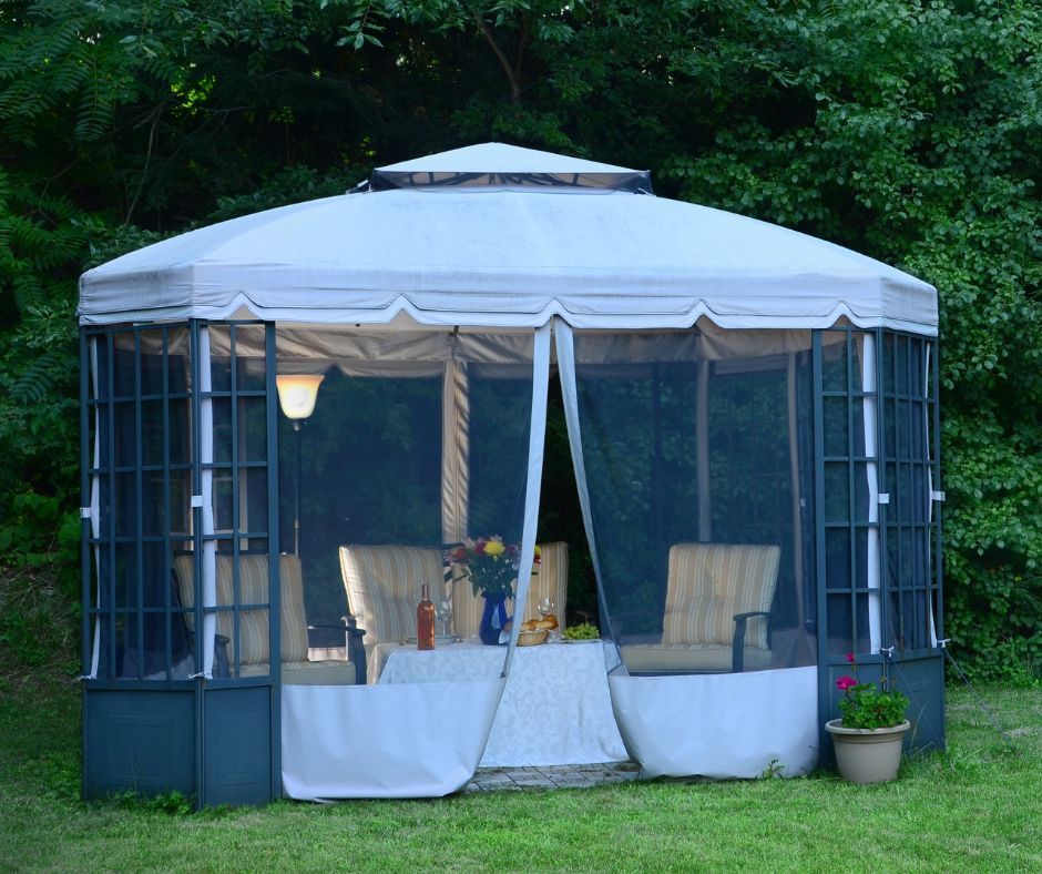 A gazebo with lattice and bug netting covering comfortable outdoor sitting area.