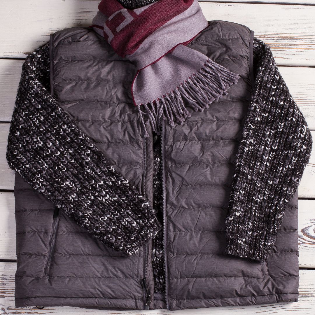 Warm padded black vest layered over sweater with a scarf.