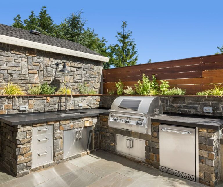 Grey stone and wood privacy fence around an outdoor kitchen.