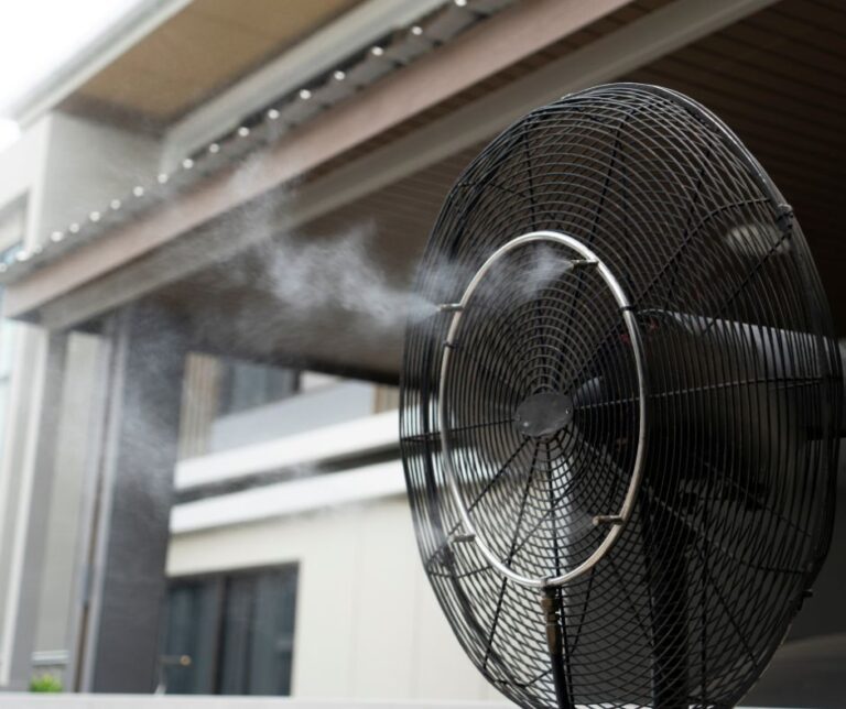 A black outdoor fan with a misting system turned on.
