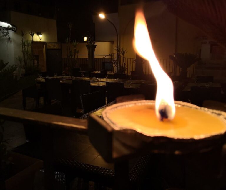 A citronella candle burning after dark on a patio.