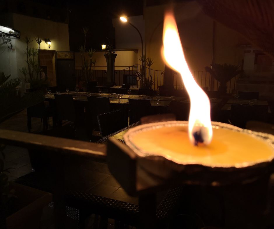A citronella candle burning after dark on a patio.