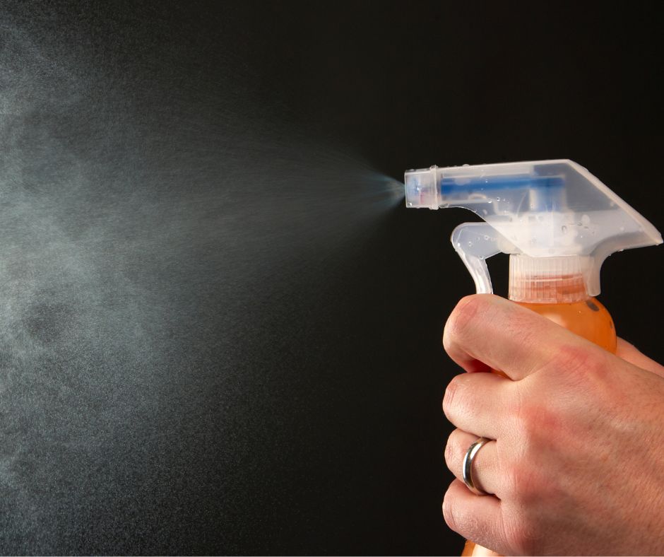 A hand squeezing a spray bottle.