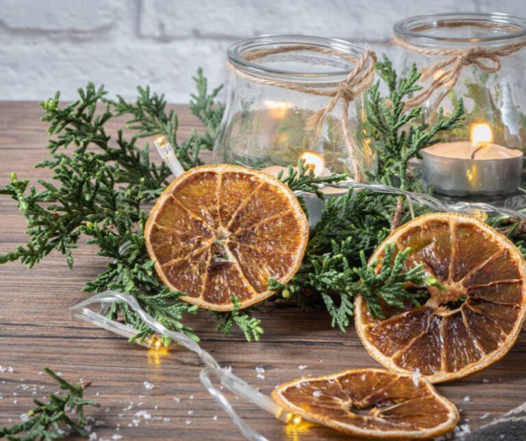 A naturally decoration center piece created with slices of dried citrus, evergreen foliage and candles.