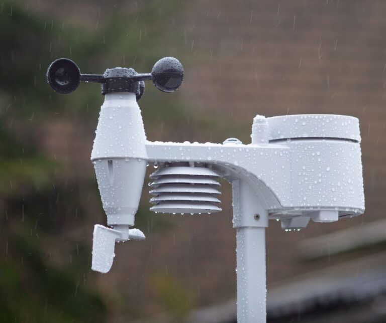 A white garden weather station operating in the rain.