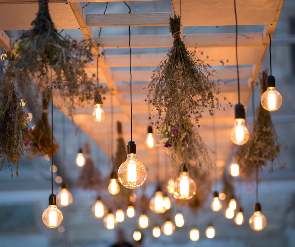 String lights and dried herbs hanging from a pergola in a garden.